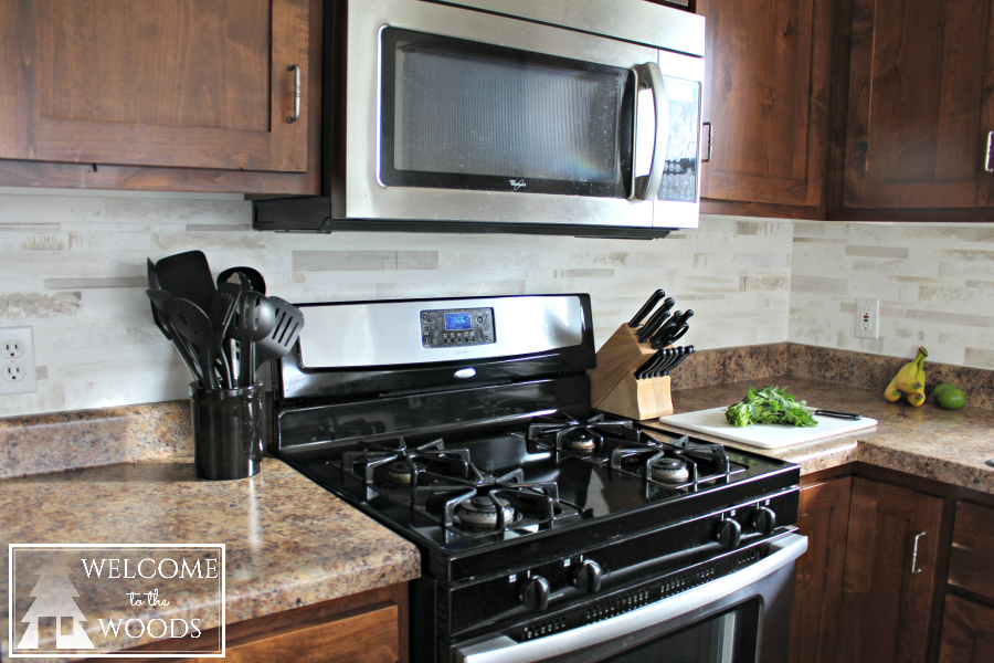 Beautiful stainless steel appliances and fake marble tile backsplash in this kitchen makeover.