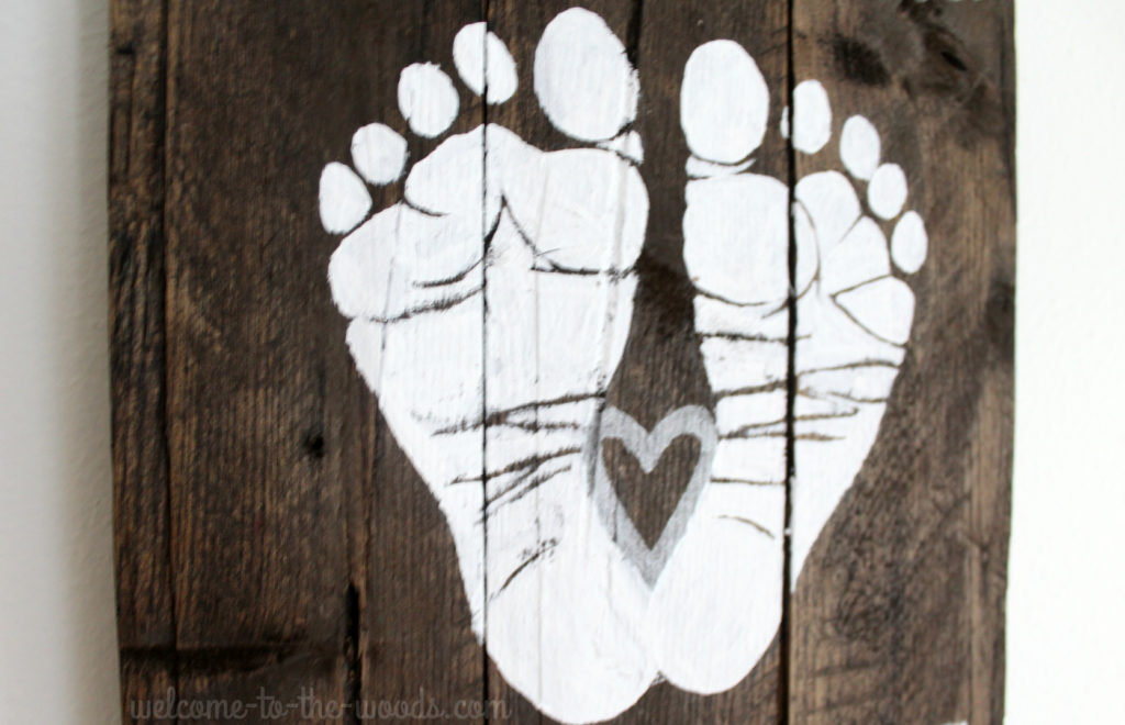 See this adorable baby shower gift idea with footprints painted on a pallet wood sign.