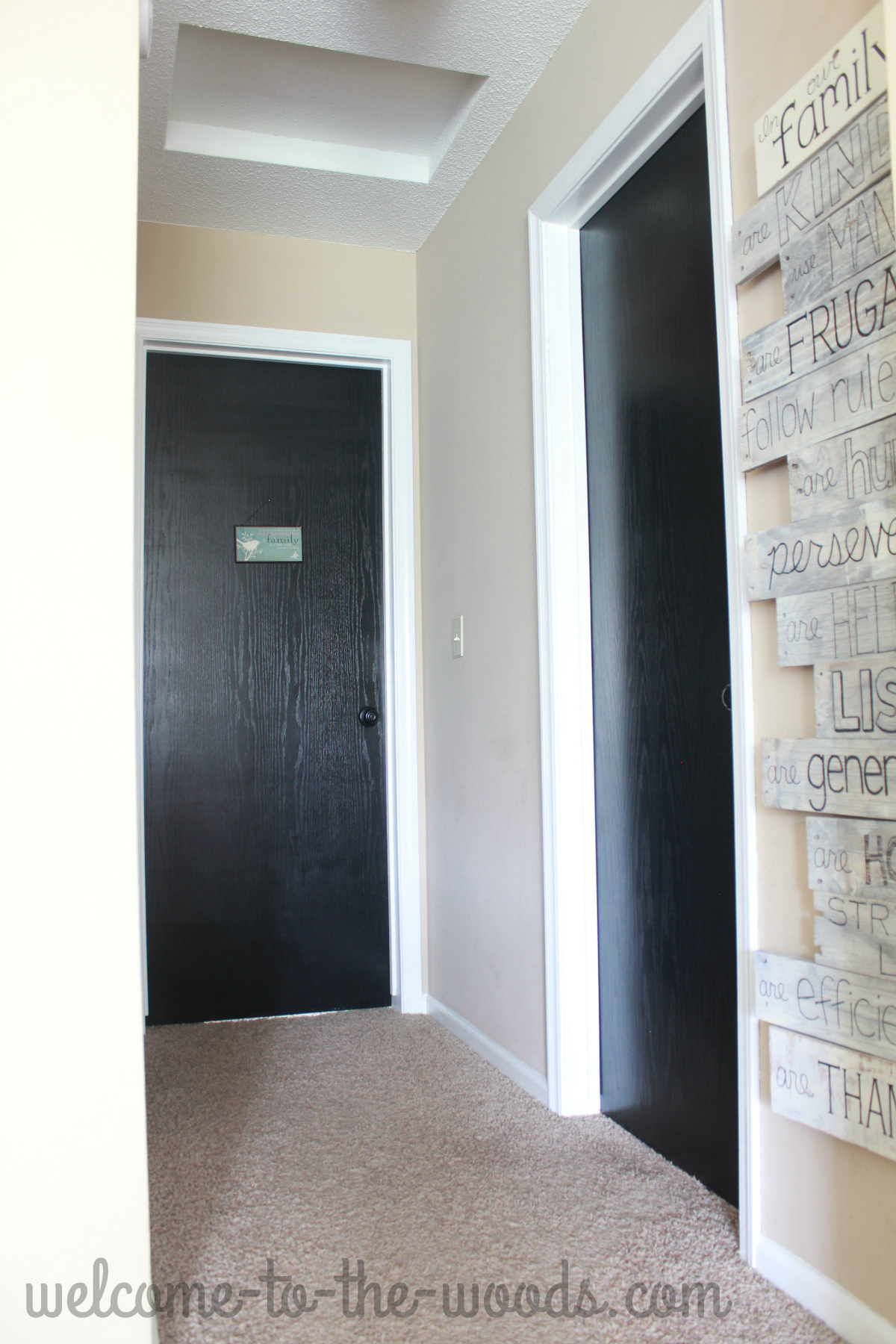 Hallway decor ideas. White trim, black doors, and a tall skinny wood pallet sign.