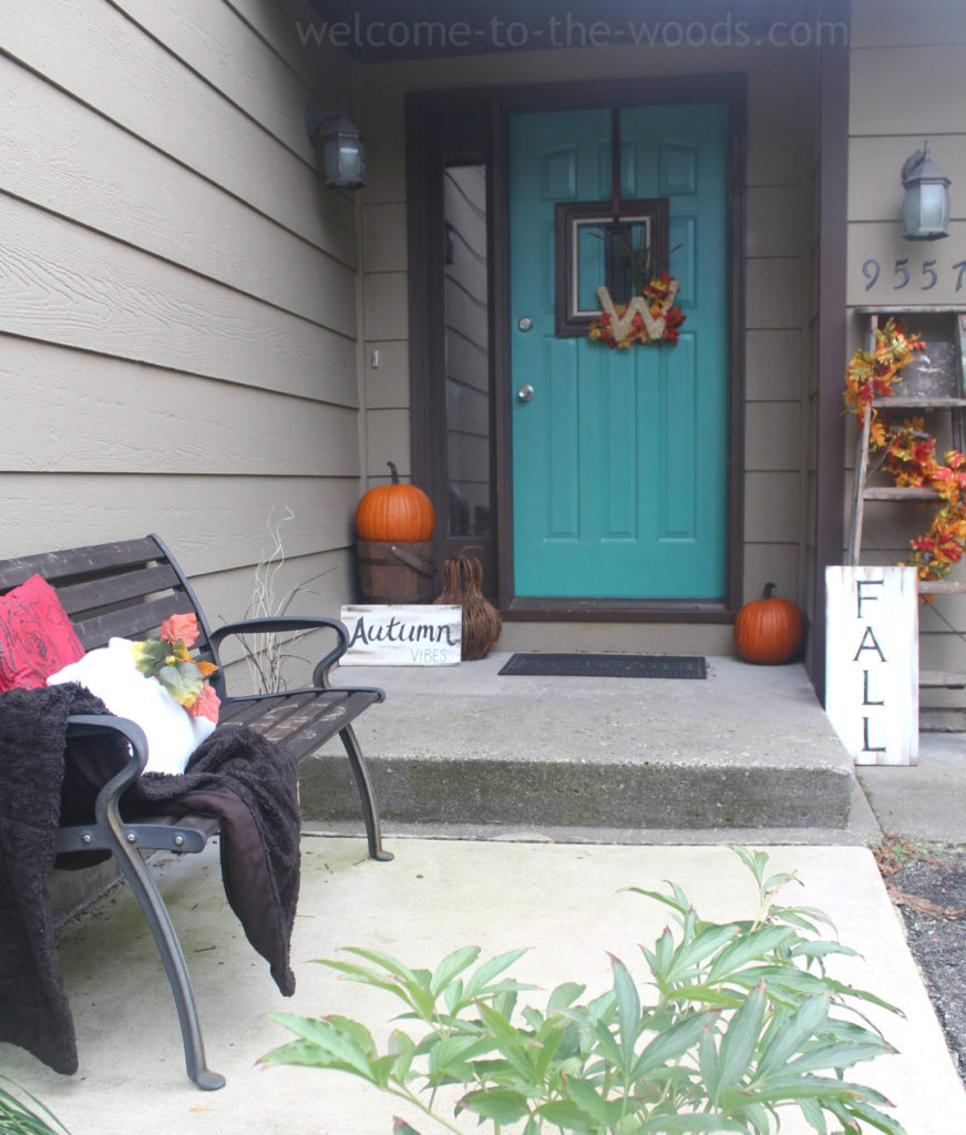 Beautiful fall front door entrance decor! Vintage items like the wood ladder and bucket as well as traditional orange colors in the leaves and pumpkins make it look so welcoming and cozy! Especially with the teal door!