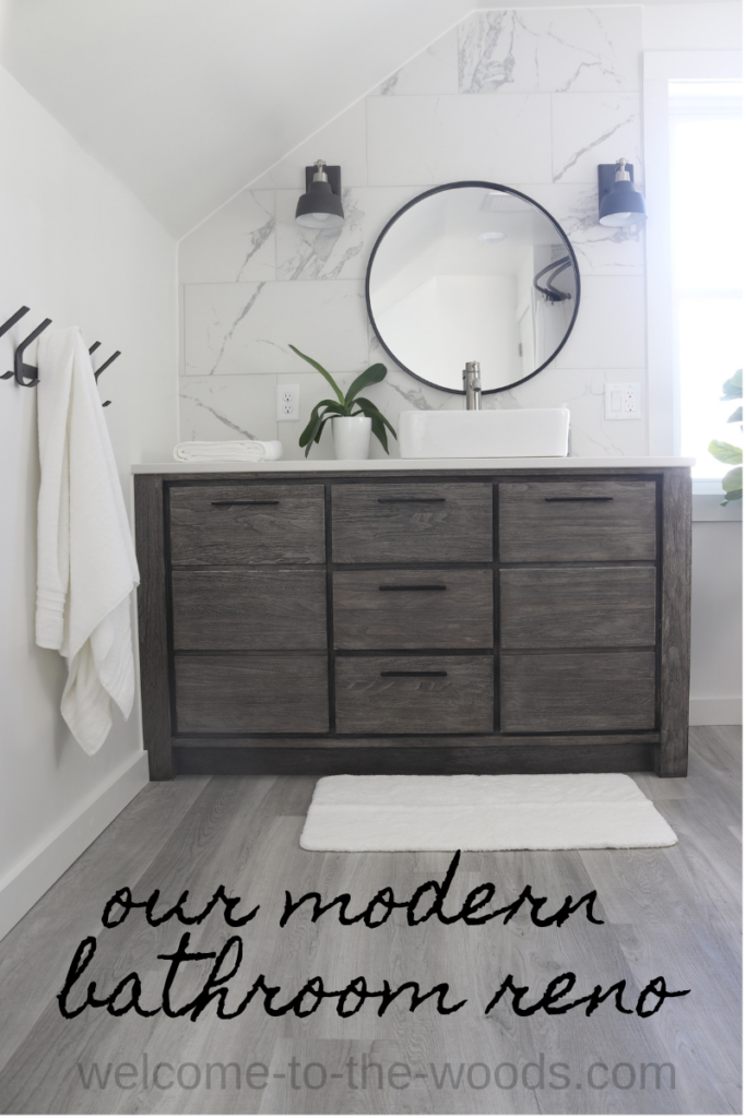 The calming color palette of this modern bathroom makes the space feel luxurious. White walls and trim highlight the subtle marble tile backsplash, gray washed teak wood vanity, and pops of matte black hardware throughout.
