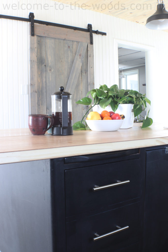 Modern farmhouse kitchen style black cabinets, wood counters, sliding barn door, chrome hardware